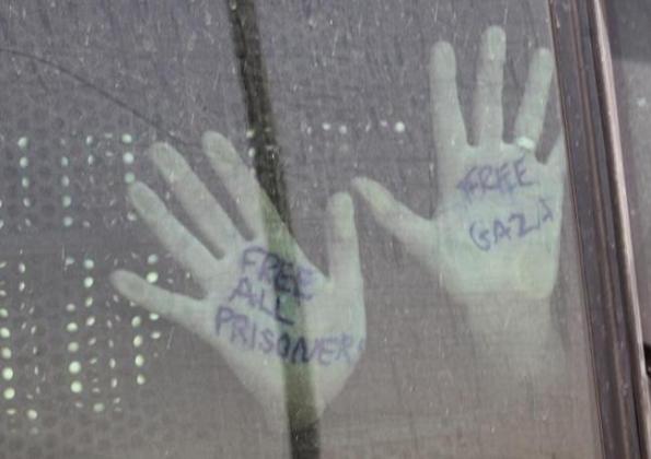 An activist places his hands against the window of a bus as it leaves Ella prison in Beersheba