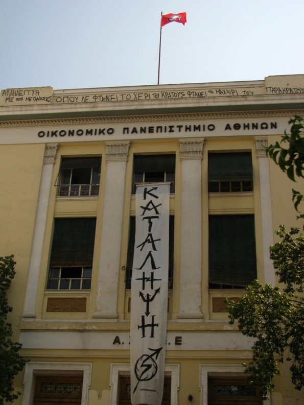 Atene, facoltà d'economia. Lo striscione urla OCCUPAZIONE mentre in alto c'è scritto "dove non arriva la mano dello stato arrivano le lame del para-stato, Solidarietà ai migranti"